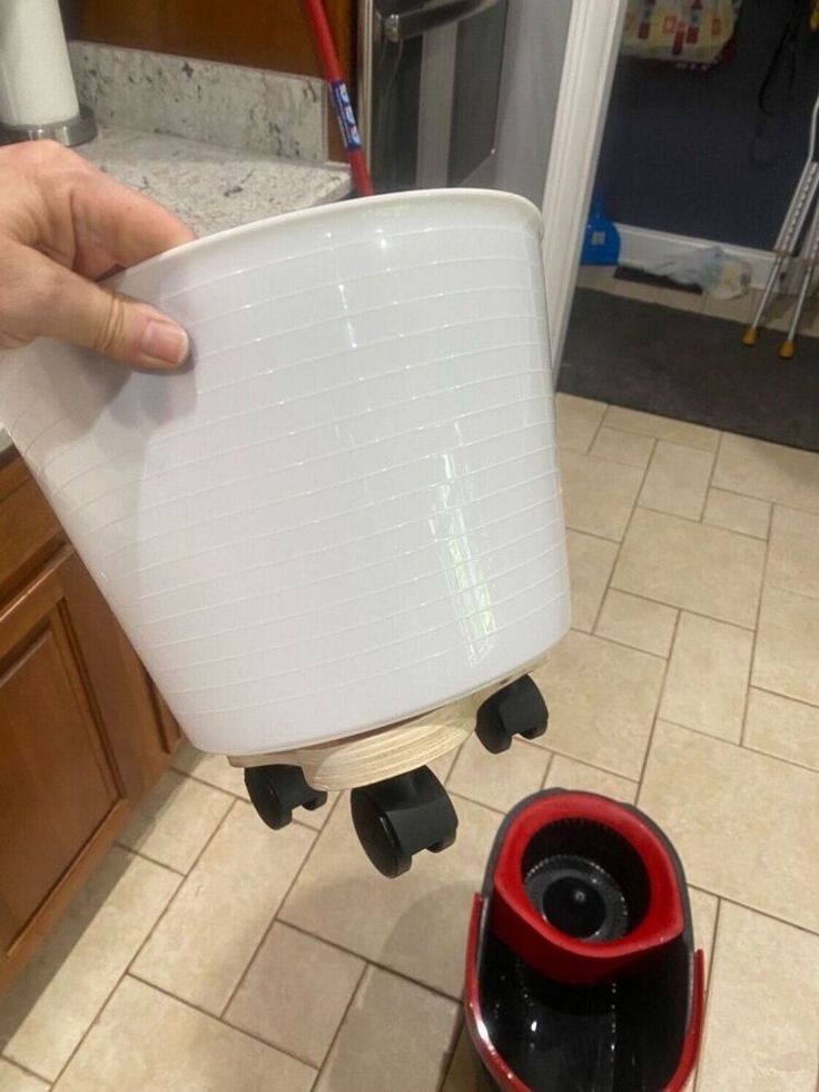 a person is holding a container over a coffee cup on a rolling cart in the kitchen