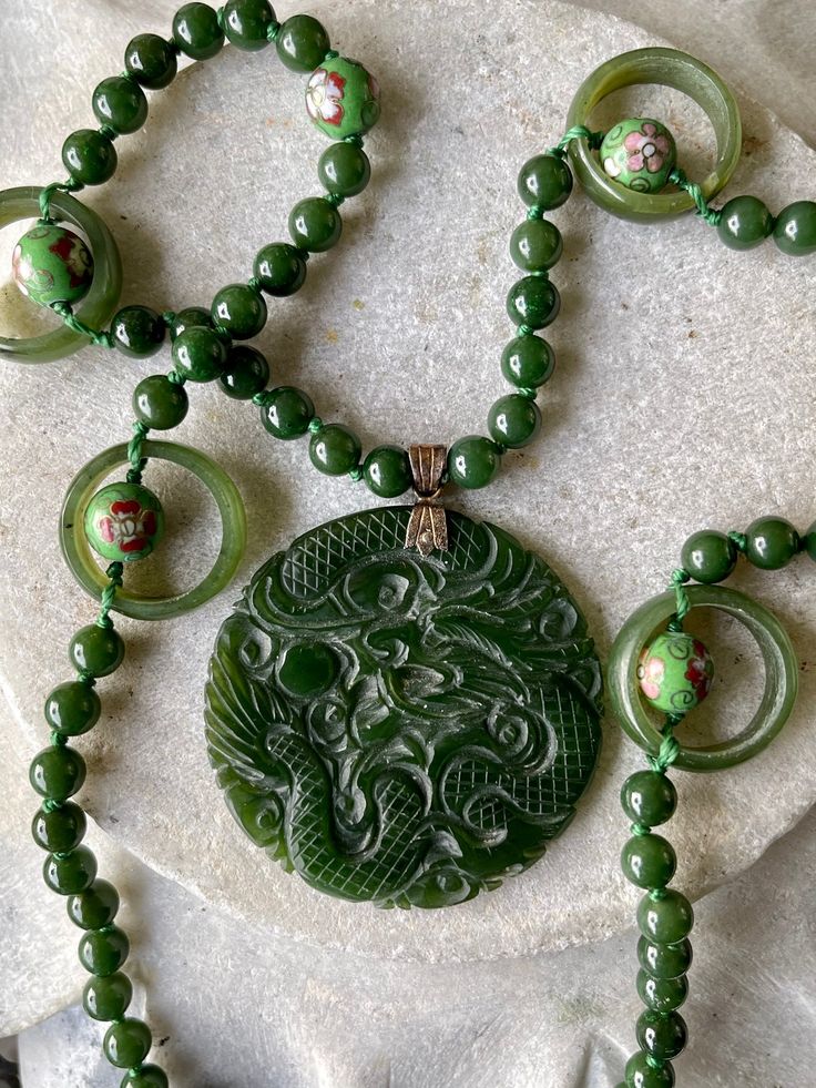 Stunning Carved Green Jade Dragon Cloisonne Long Vintage Necklace Measures 24 inches around not including pendant Jade Amulet Necklace With Round Pendant, Jade Amulet Pendant Necklace, Spiritual Jade Round Pendant Necklace, Round Jade Spiritual Necklaces, Spiritual Round Jade Necklaces, Spiritual Round Jade Necklace, Round Jade Necklace For Spiritual Style, Green Amulet Pendant Necklace, Spiritual Jade Jewelry With Large Pendant