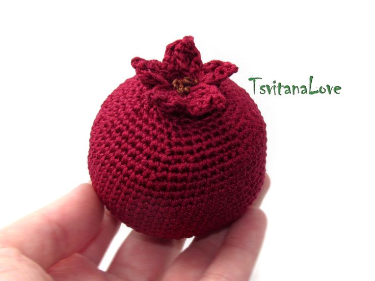 a crocheted red bag with a flower on the top in someone's hand