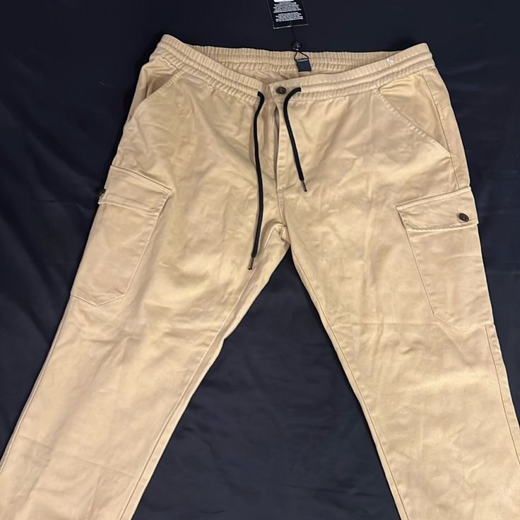 Brand New With Tags. True Religion Denim. Khaki 6-Pocket Cargo Pants. Mid-rise Beige Cotton Cargo Jeans, Casual Cargo Jeans With Tapered Leg, Mid-rise Beige Cargo Jeans With Side Pockets, Casual Tapered Leg Jeans With Cargo Pockets, Tapered Leg Cotton Cargo Jeans, Urban Beige Pants With Pockets, Urban Beige Cargo Bottoms, Beige Urban Cargo Bottoms, Urban Style Beige Cargo Bottoms