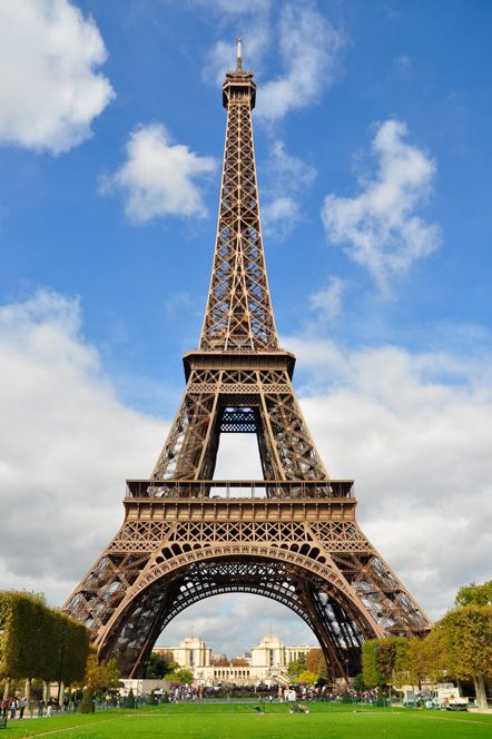 the eiffel tower is very tall and has many people standing around in front of it