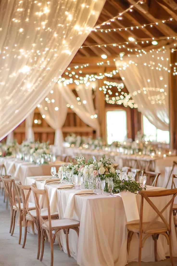 the tables are set with white tablecloths and lights strung from the ceiling above them