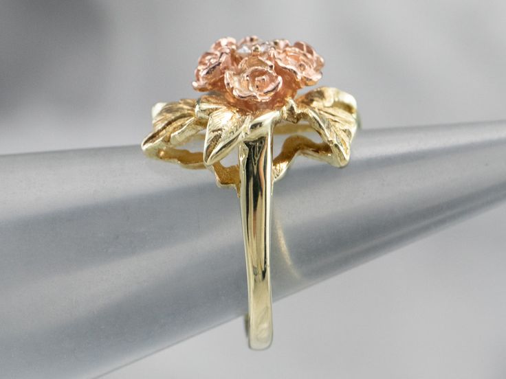 This pretty ring was crafted by the mid-century, with 14 karat gold in leaves and roses of rose gold forming a sweet bouquet center. This pretty piece has a stunning round brilliant diamond, a sparkling contrast to the softly textured petals of the flower.Metal: 14K Yellow and Rose GoldGem: Diamond .11 Carats, SI1 in Clarity, G in ColorGem Measurements: 3.0 mm, RoundRing Size: 4.75 Formal Flower Shaped Rings With Rose Design, Rose Flower Ring For Anniversary, Fine Jewelry, Formal Flower-shaped Ring With Rose Design, Rose-colored Fine Jewelry Flower Ring For Anniversary, Formal Flower Shape Rose Design Ring, Formal Flower-shaped Rose Design Ring, Formal Rose Flower Shaped Rings, Formal Rose Flower Rings, Formal Rose Colored Flower Shaped Rings