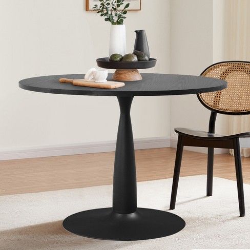 a black table with two chairs and a vase on it in front of a white wall