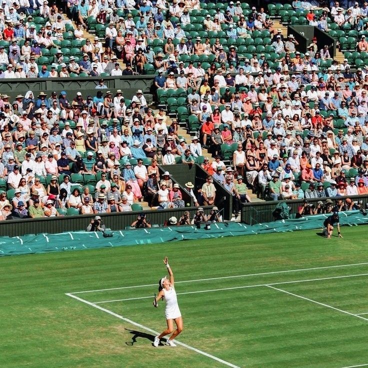 a tennis player serving the ball in front of an audience