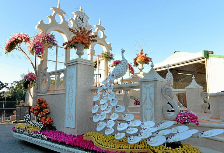 there is a float decorated with flowers and plates in the shape of a peacock on display