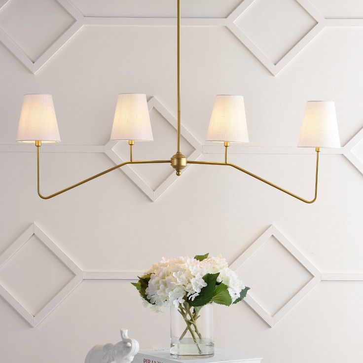 a vase with white flowers on top of a table next to a wall mounted lamp