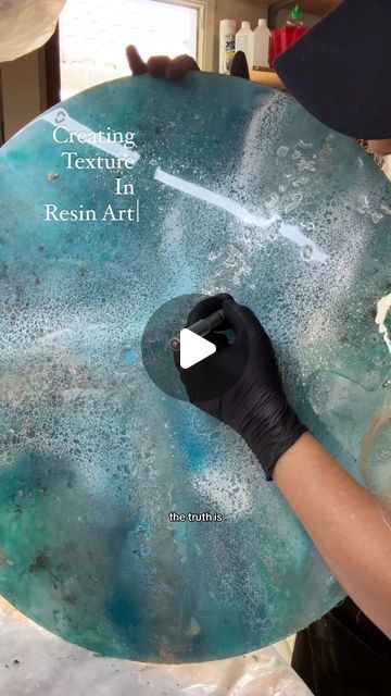 a person holding a blue plate with white paint on it and the words creating texture in resin art