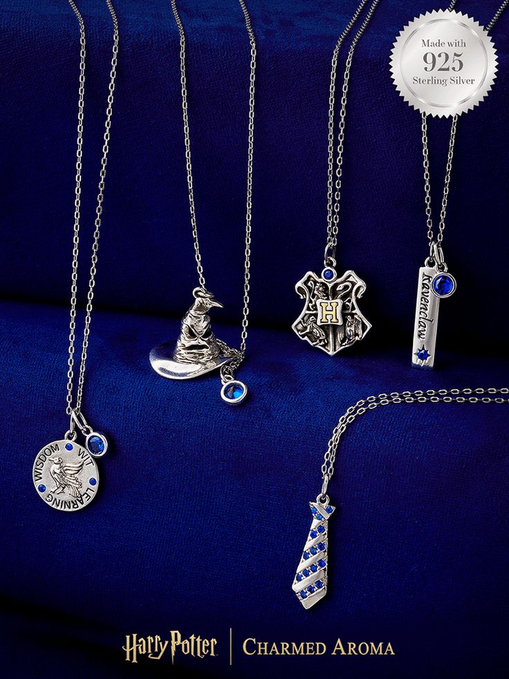 harry potter charms and necklaces are displayed on a blue velvet background with silver seal