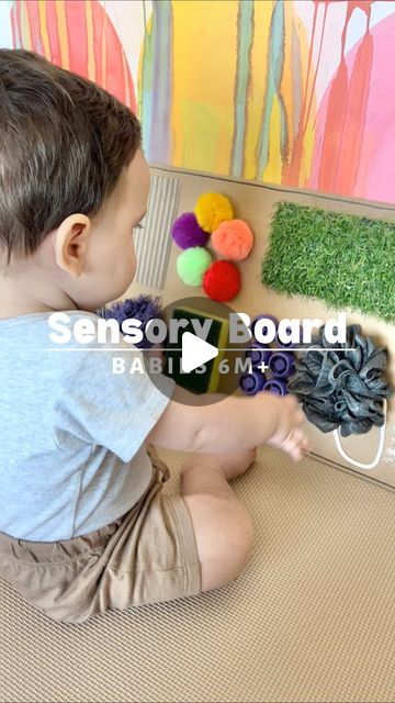 a young boy sitting on the floor playing with some fake grass and balls in front of him