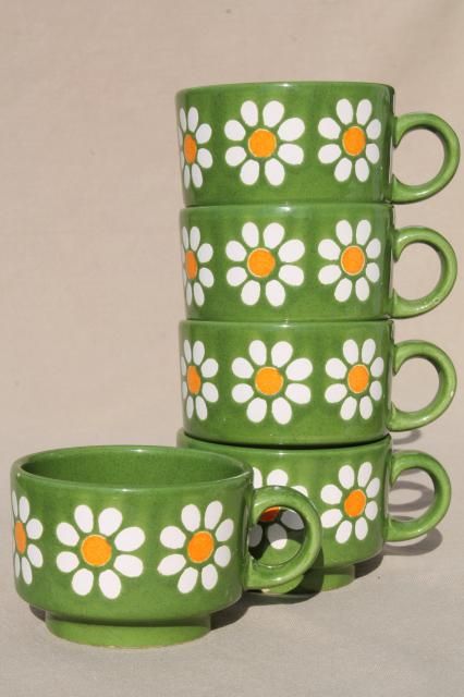 four green mugs with orange and white flowers on them are stacked in the same pattern