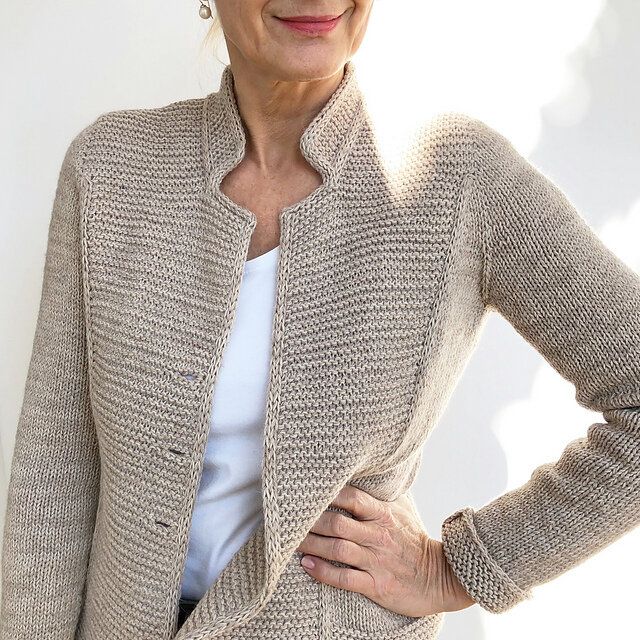 an older woman standing with her hands on her hips, wearing a cardigan sweater and jeans