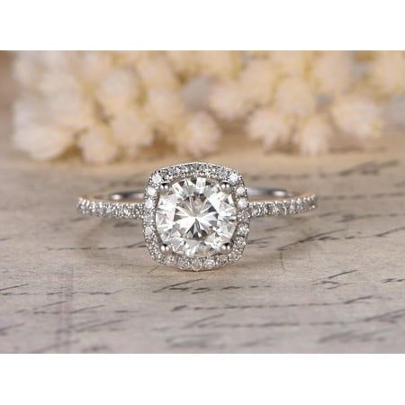 a white gold engagement ring with an oval diamond center surrounded by pave diamonds on a piece of wood