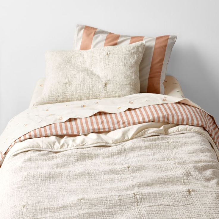 an unmade bed with two pillows on top of it and a striped comforter