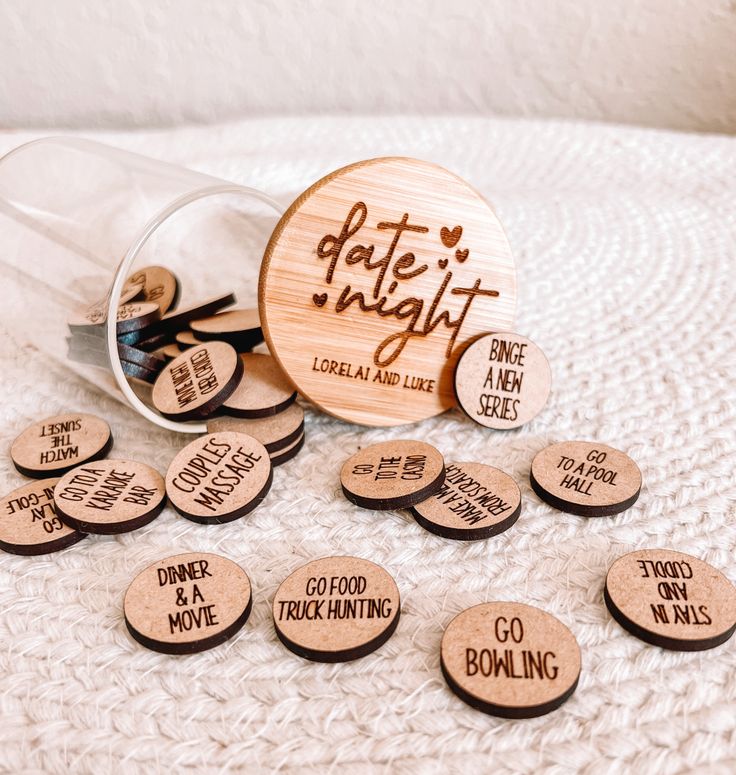 some wooden magnets that say date night and one is in a glass jar on a white blanket