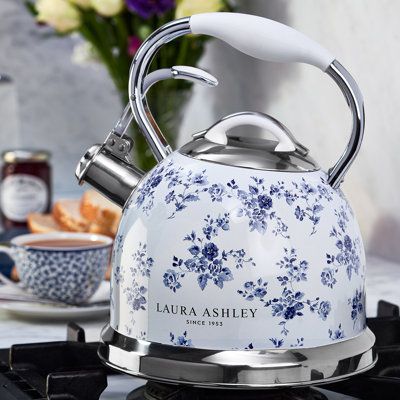 a blue and white tea kettle sitting on top of a stove next to some flowers