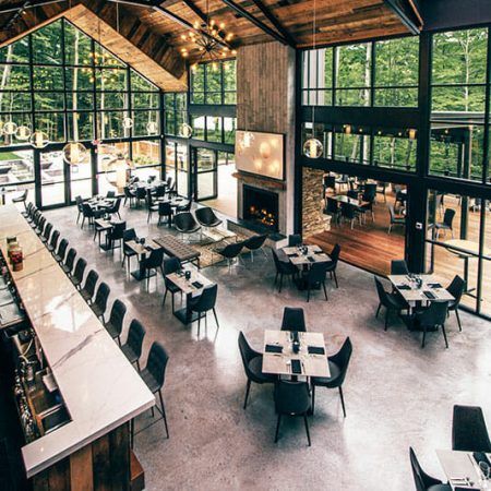 an empty restaurant with tables and chairs in front of large windows that look out onto the woods