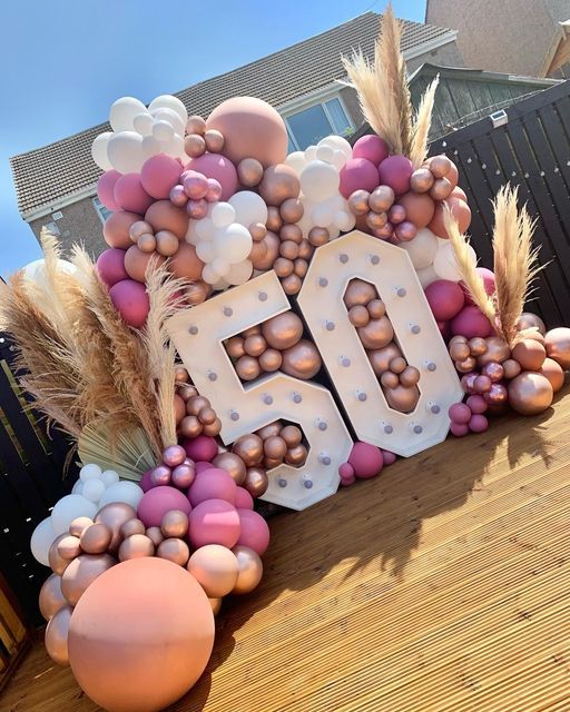 a sign that says 50 with balloons and flowers on the front yard, in front of a house