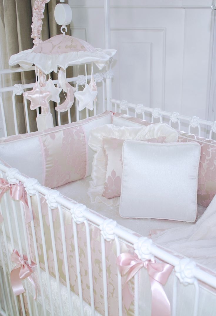 a baby crib with pink and white decor