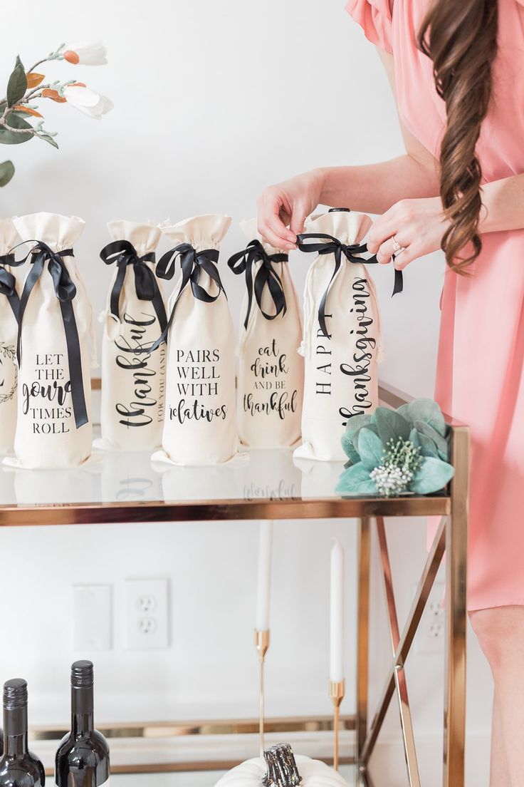 a woman standing in front of three wine bags on a table with flowers and candles