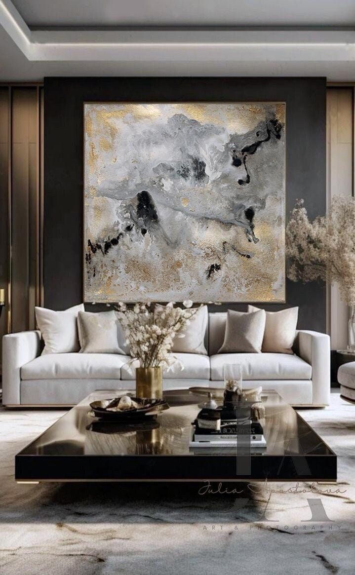 a living room filled with furniture and a large painting on the wall above it's coffee table