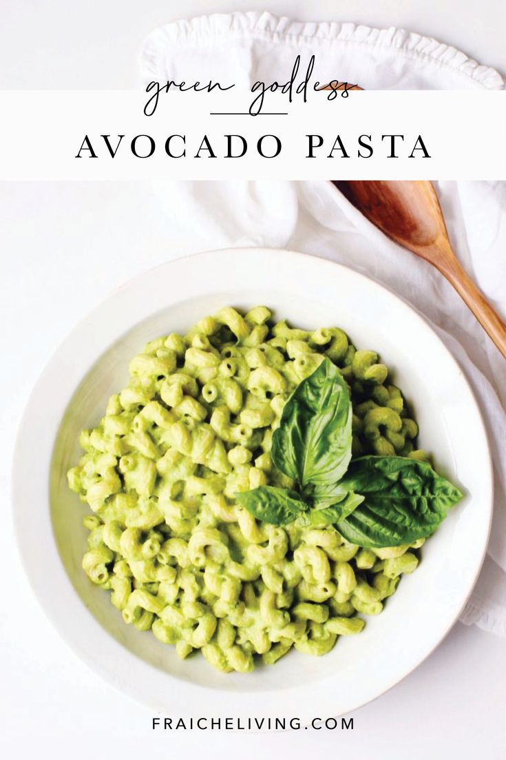 a white bowl filled with green pasta and basil