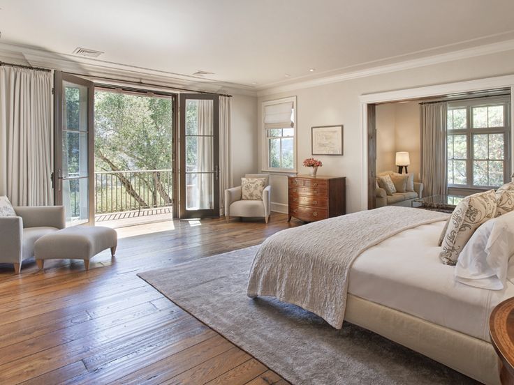 a large bedroom with hardwood floors and white walls, along with sliding glass doors that lead to an outdoor deck