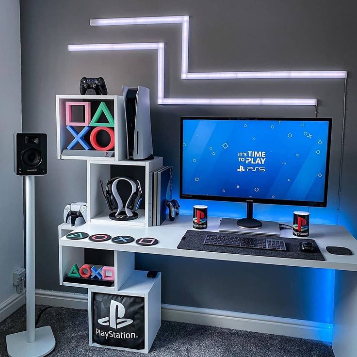 a desk with a computer, speakers and other electronic equipment on it in front of a gray wall