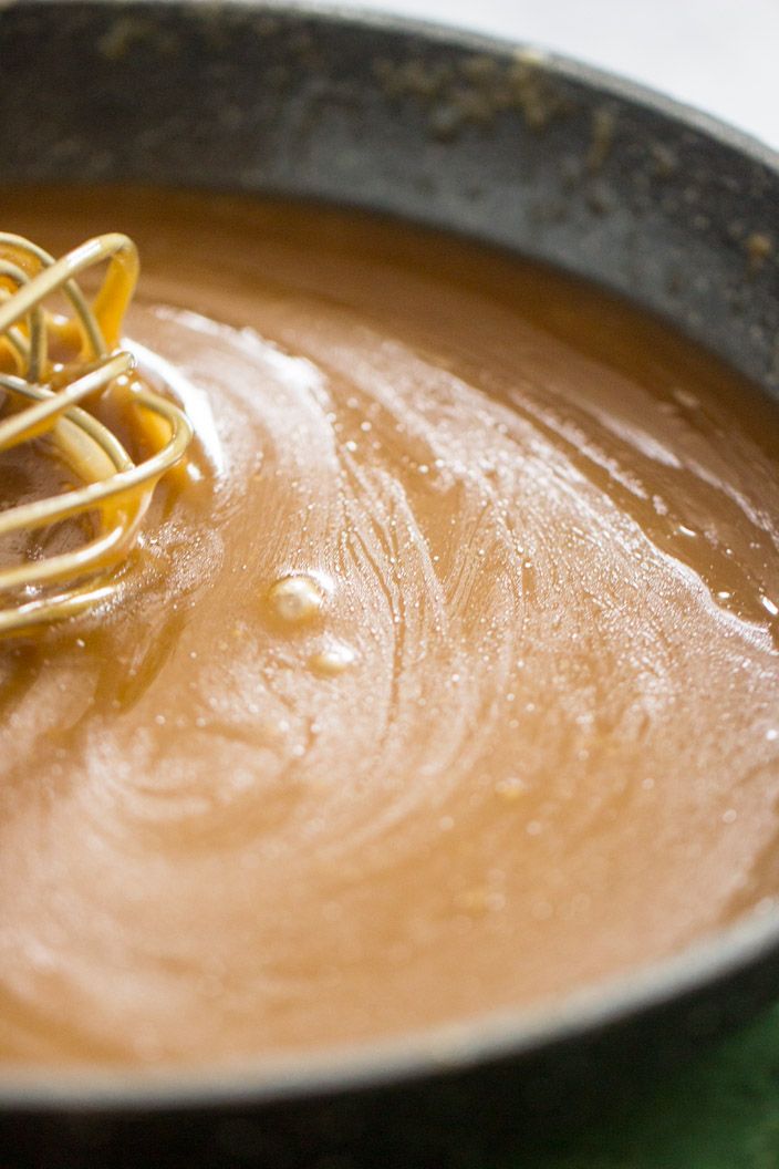 a whisk is being used to make peanut butter caramel sauce in a skillet