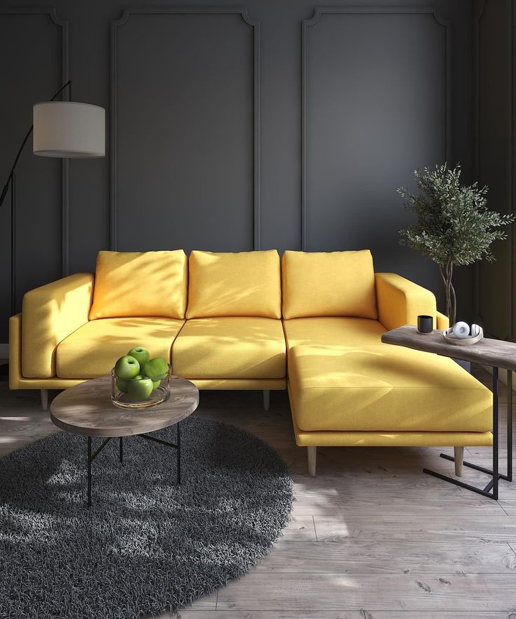 a living room with a yellow couch and coffee table in front of a gray wall