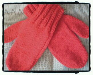 two red mittens sitting on top of a table