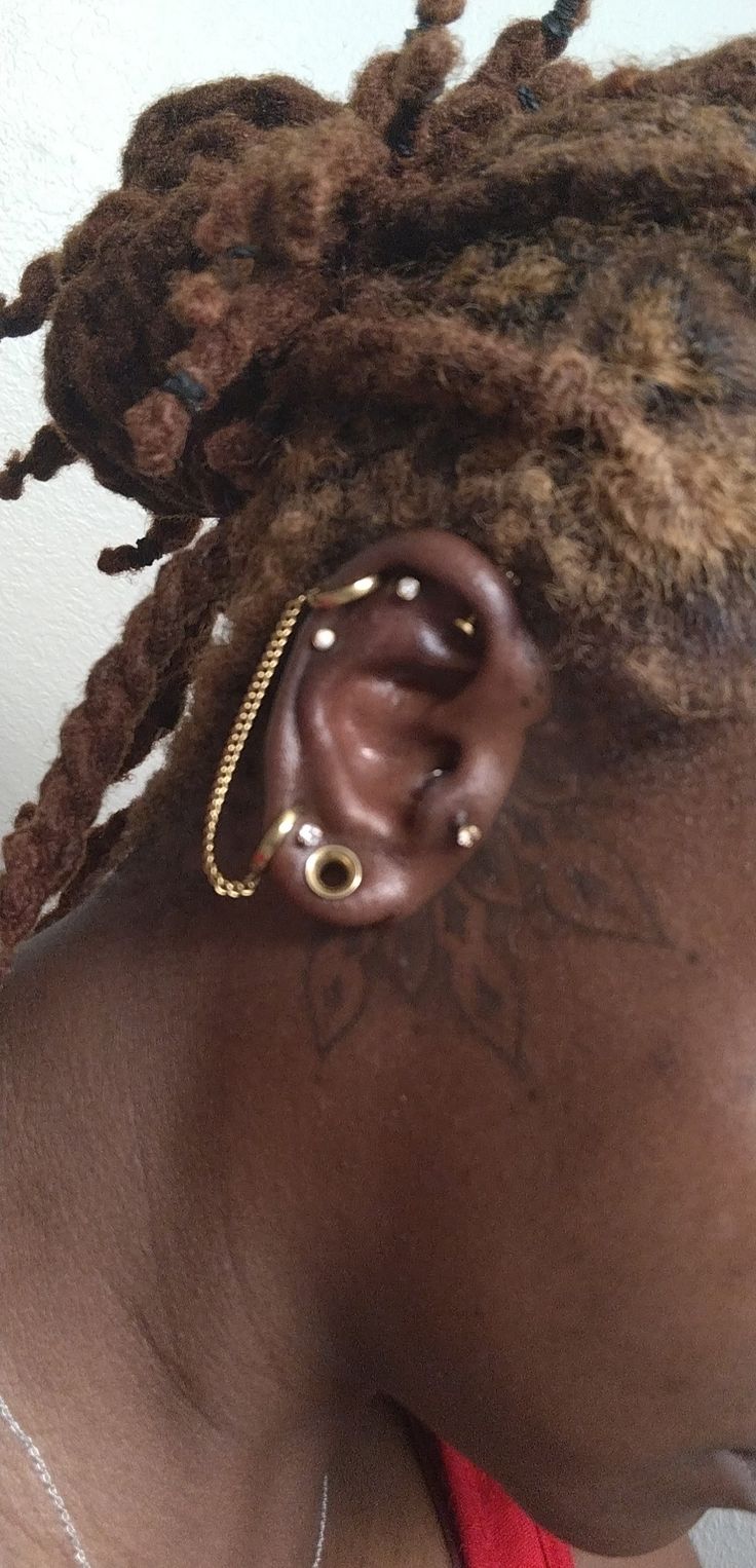 a close up of a person with ear piercings on their ears and hair in dreadlocks