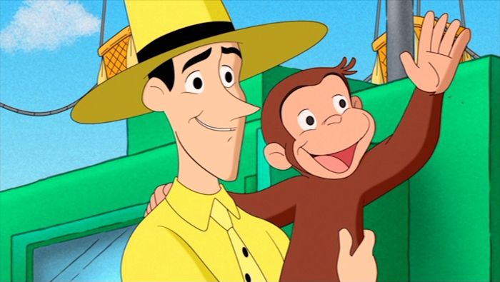 a man in a yellow shirt and hat holding up a monkey with his arm around another man's neck