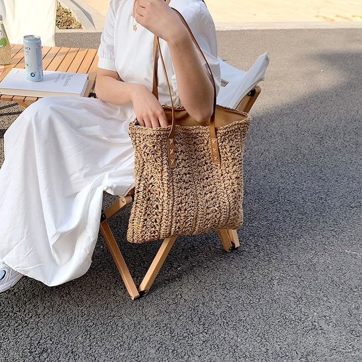 a woman sitting on a chair with a straw bag