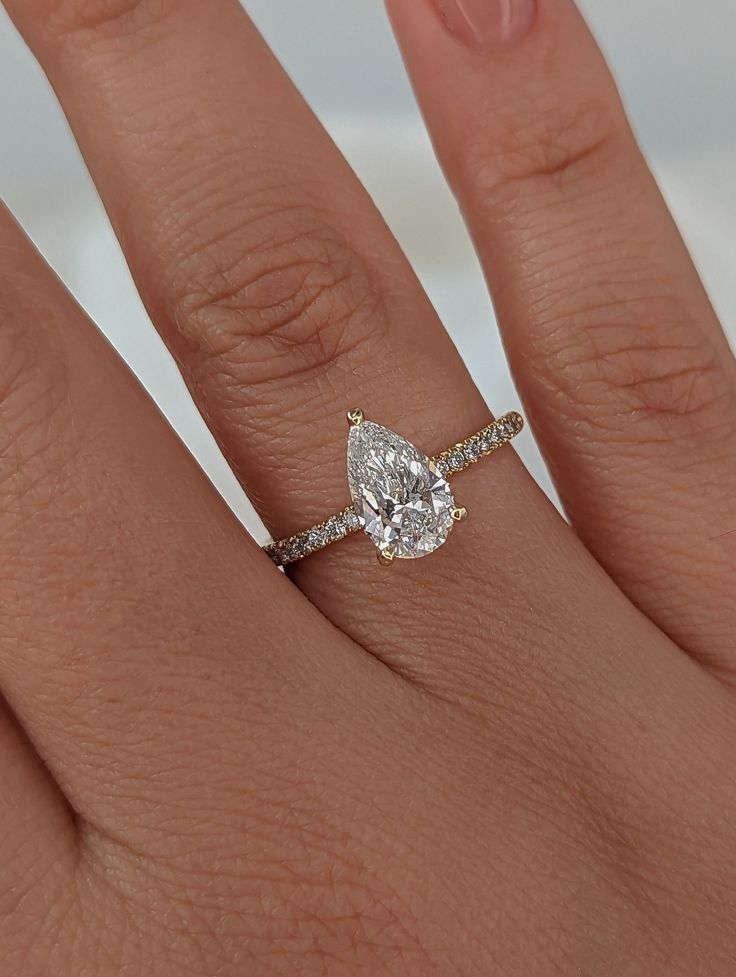 a woman's hand with a diamond ring on top of her finger and an engagement band