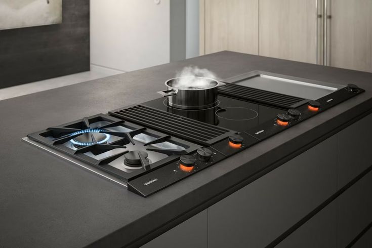 a black stove top sitting on top of a counter next to a pot and pan