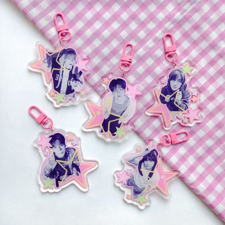 four keychains with pictures of people on them sitting next to a pink checkered tablecloth