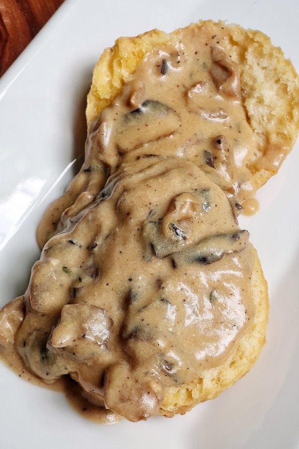 a white plate topped with biscuits covered in gravy