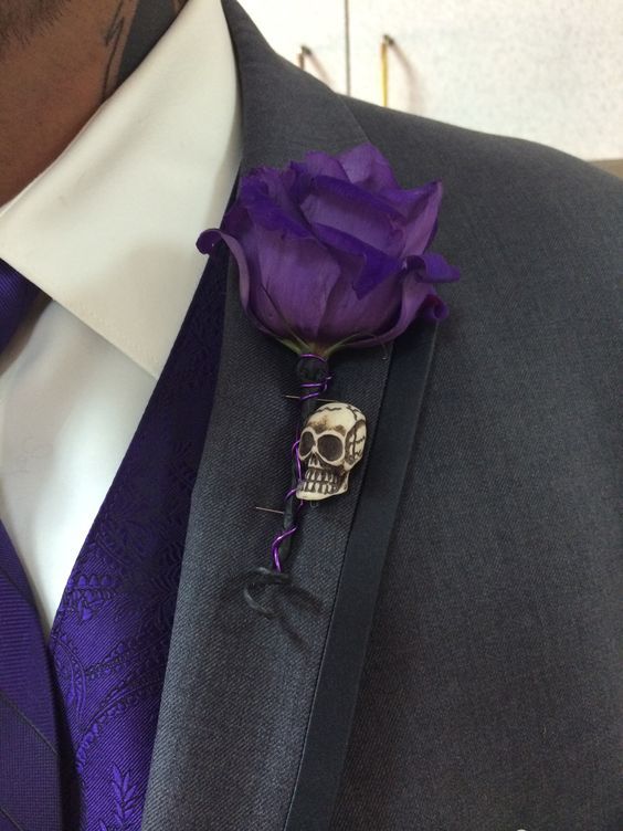 a man wearing a suit and tie with a skull brooch on it's lapel