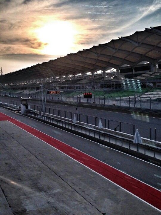 an empty race track with the sun setting in the background