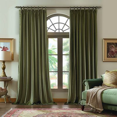 a living room filled with furniture and a large window covered in green drapes next to a rug