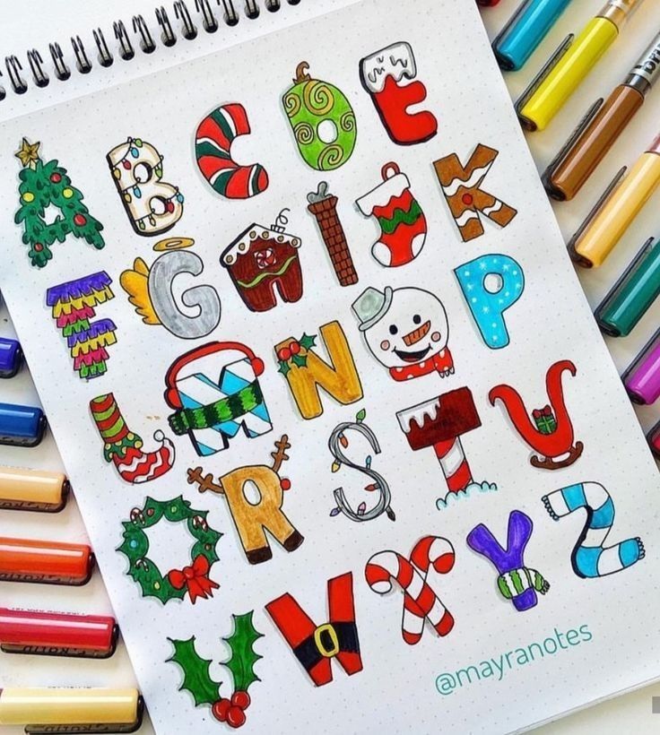 an open notebook with christmas themed letters and crayons