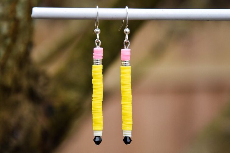 two pairs of yellow and pink earrings hanging from a hook