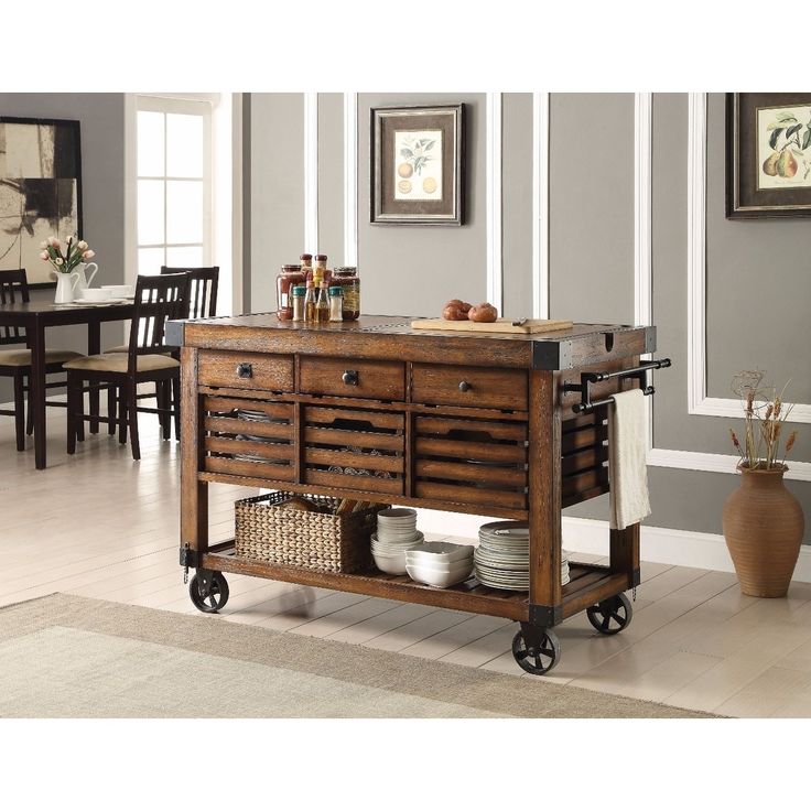 a kitchen island with drawers and baskets on it in front of a dining room table