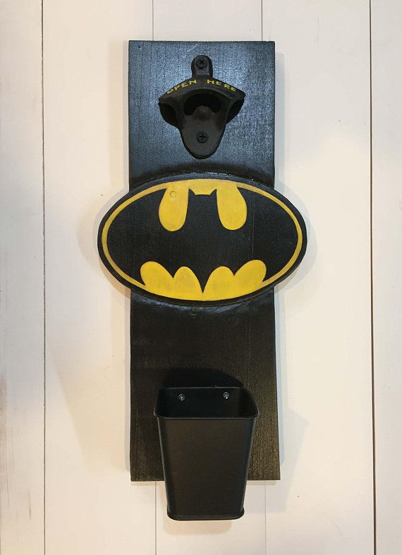 a batman bottle opener mounted to the side of a white wall with a black trash can