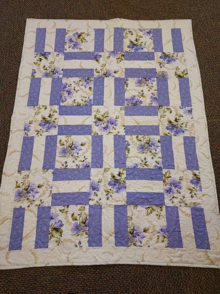 a purple and white quilt with flowers on it