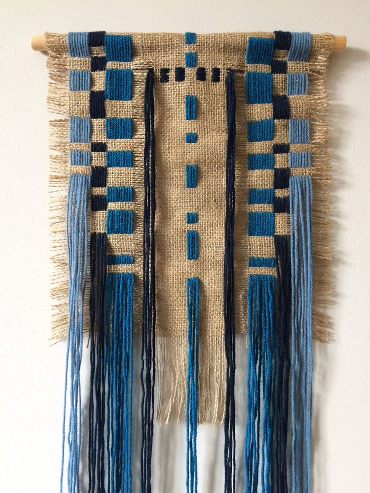 a wall hanging made out of jute and blue yarn with fringes on it