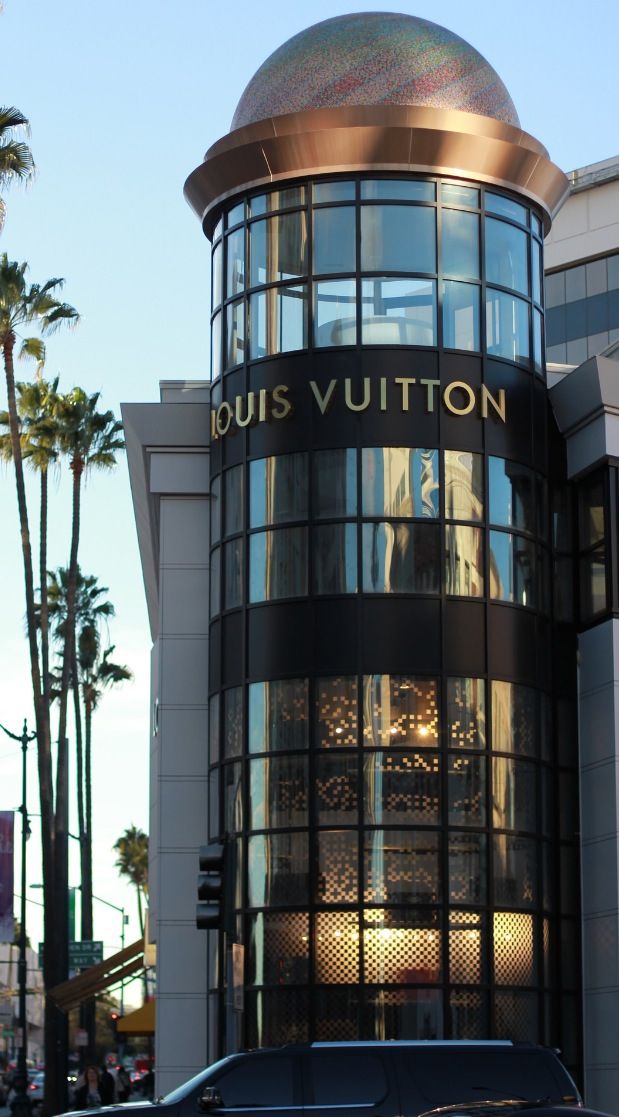 a black van is parked in front of a building with palm trees on the street