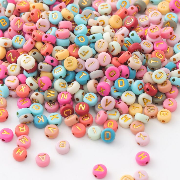 colorful beads with letters are scattered on a white surface, including the letter s and m