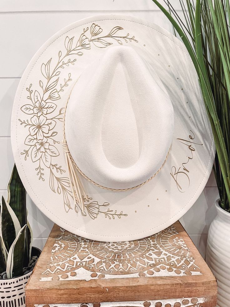 a white cowboy hat sitting on top of a wooden table next to potted plants